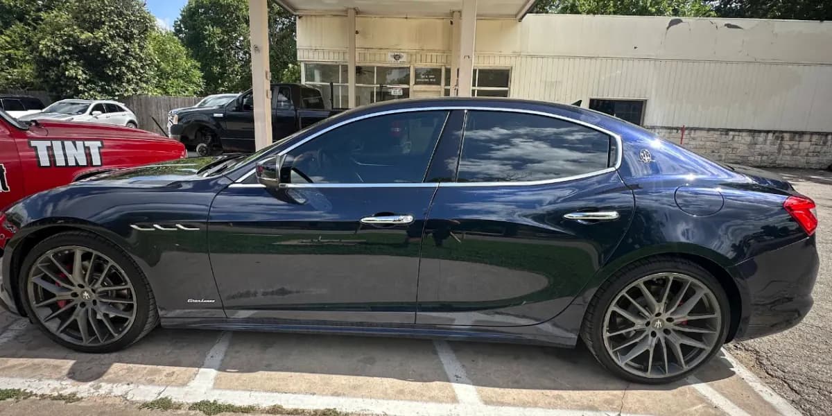 Navy Maserati Ghibli with window tint installed, outside the Shade Customs shop in Georgetown, Texas