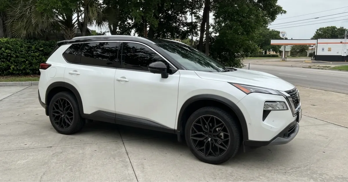 White Nissan Rogue with window tint installed, outside the Shade Customs shop in Georgetown, Texas